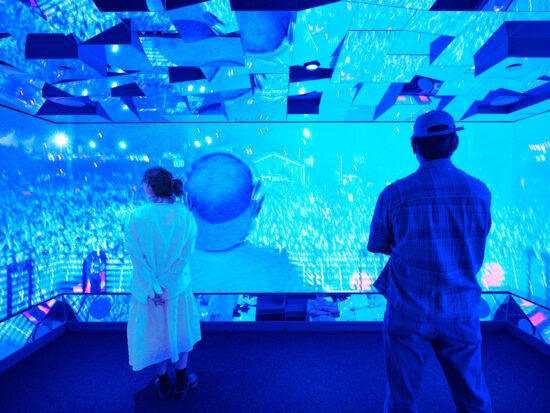 Två gäster i spegelrummet i ett blått sken på Avicii Experience